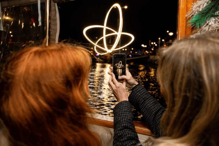 Two people photograph light trails on a boat at night.